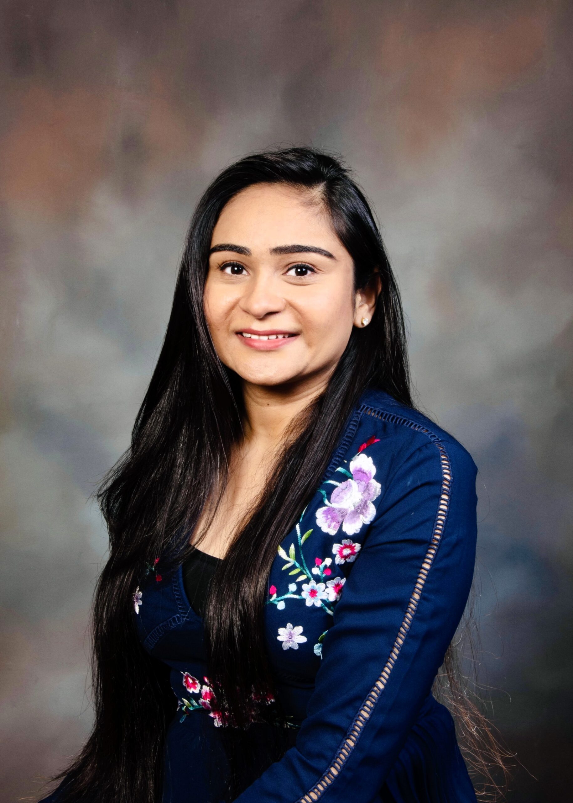 Dr. Krishna Mehta Professional portrait of Dr. Krishna Mehta smiling in a navy floral dress against a neutral studio background